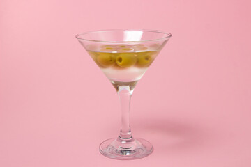 Martini glass with olives on a pink background. Delicious alcoholic drink.
