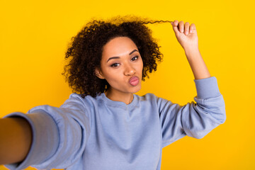 Portrait of attractive lovely lady make selfie kiss lips hand touch hair isolated on yellow color background