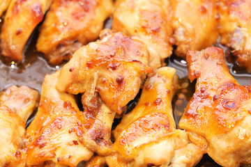 Backed chicken wings parts with garlic in grill skillet close up food photo. Fresh roasted poultry from oven. Homemade kitchen. Cooking at home.