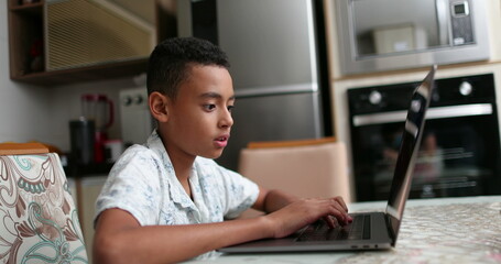 Fototapeta na wymiar Hispanic child using laptop at home browsing internet online