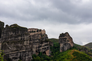 Fototapeta na wymiar Scenic view of Holy Monastery of St Nicholas Anapafsas seen from forest on cloudy day, Kalambaka, Meteora, Thessaly, Greece, Europe. Dramatic landscape. Landmark build on unique rock formations