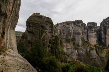 Panoramic view of unique rock formations near Holy Monastery of Varlaam on cloudy foggy day in Kalambaka, Meteora, Thessaly, Greece, Europe. Rocks overgrown with green moss creating moody atmosphere
