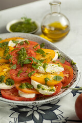 Close up of Caprese salad with yellow and red tomato on browm background. Italian cuisine.