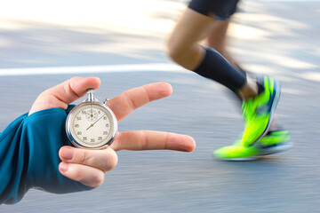 measuring the running speed of an athlete using a mechanical stopwatch. hand with a stopwatch on...