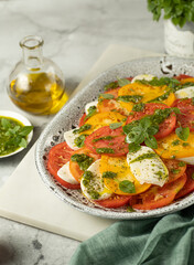 Close up of Caprese salad with yellow and red tomato on browm background. Italian cuisine.