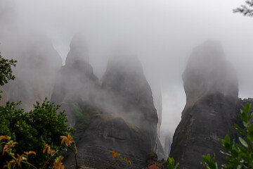 Panoramic view of unique rock formations near Holy Monastery of Varlaam on cloudy foggy day in Kalambaka, Meteora, Thessaly, Greece, Europe. Fog surrounding the dramatic landscape, moody misty vibes