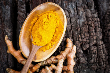 Turmeric powder in wooden spoon on old wooden table. herbal