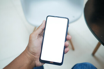 POV of young man hand using smart phone with empty screen sitting on chair 