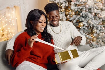 Portrait of happy black couple holding gifts and sitting on a coach