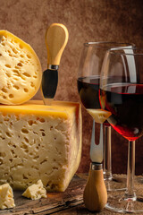 Red Wine And Assorted Cheese Plate maasdam with big holes on a wooden background. place for text
