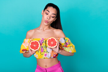 Photo of sweet doubtful young woman grapefruit halves cover boobs want surgery isolated cyan color...