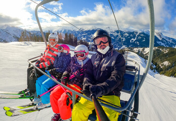 Family riding ski lift cable car on winter vacation skiing.