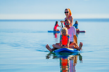 Happy Family on SUP stand up paddle on vacation. - obrazy, fototapety, plakaty