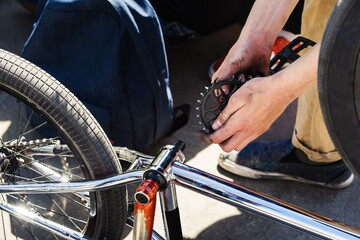 Bmx bike chassis repair. The guy examines the detail of the sprocket and the pedal. Preparation for competitions and maintenance of a sports bike. Close-up