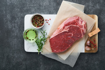 Steaks. Fresh New York Steaks raw with spices rosemary and pepper on black marble board on gray...