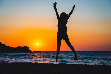 Silhouette of a child jumping in sunset on a beach.