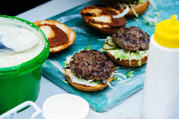 Cooking burger at home. Bread and cutlets as well as condiments are located on the kitchen table. selective focus