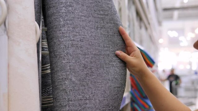 Close-up of a woman choosing wallpaper in a construction goods store.