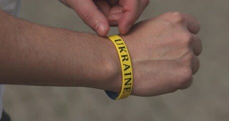 Hand with blue and yellow wristband , colours of flag of Ukraine.