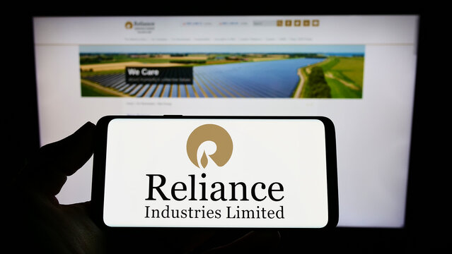 Stuttgart, Germany - 09-22-2022: Person holding cellphone with logo of Indian company Reliance Industries Limited on screen in front of business webpage. Focus on phone display.