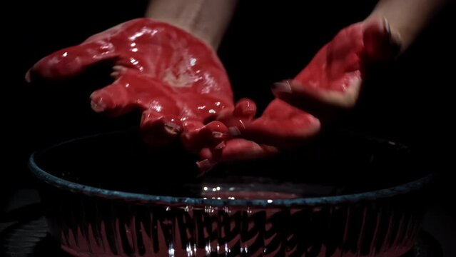 Female hands covered in blood washes her hands close-up in the dark. Bloody mess. Terrible bleeding. Crimson drops of blood fall to the surface. Scarecrows with blood.