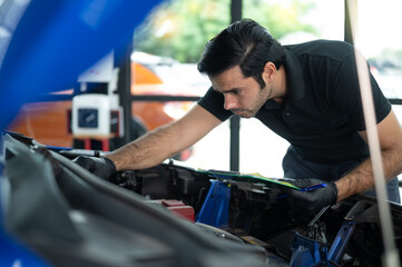 Mechanic Asian Arab man close up using laptop computer and diagnostic software to tuning fixing repairing car engine automobile vehicle parts using tools equipment in workshop garage support services