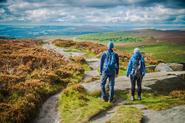 Fototapeta na wymiar Hill walkers heading along Burbage edge in the peak District of the Derbyshire dales
