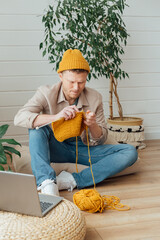 Middle aged man knitting at home. Knitting project in progress. Man learning a new hobby - 533702362