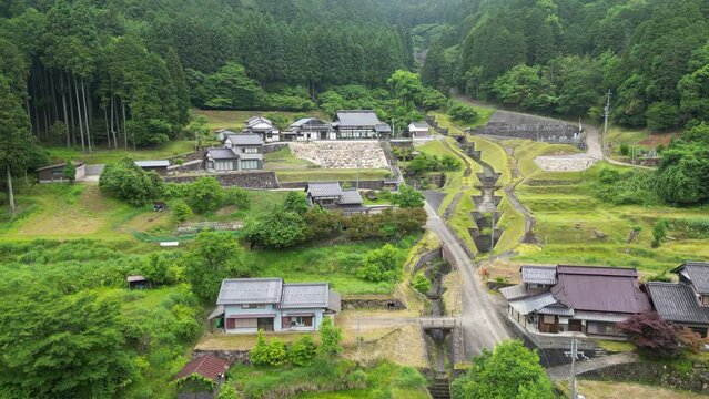 Rise and tilt down over small mountain farming community and managed stream