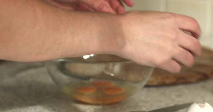 Man breaking egg big glass bowl with eggs cooking omelet on the breakfast kitchen interior.