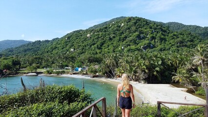 Santa Marta Colombia , Tayrona Natural Park Caribbean sea Cabo San Juan  - Drone aerial view blond lady girl looking the amazing  sand beach and bay with  forest during the travel in South America