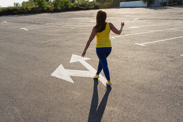 Woman walking on asphalt with arrow symbol