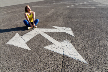 Woman sitting cross-legged on three way direction arrow sign