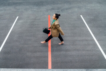 Businesswoman walking over red line at parking lot