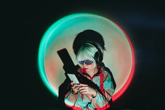 Woman using smart phone standing against black background with spot lit