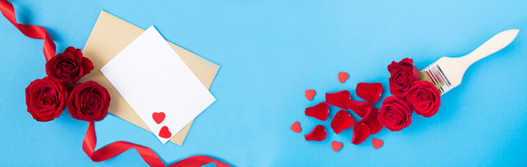 Top view of empty white paper for text, paintbrush with red roses and hearts on the blue background.Banner. Copy space.