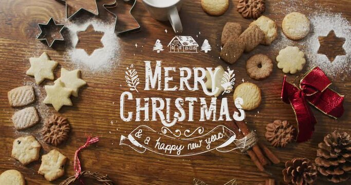 Animation of merry christmas over cookies and decorations on wooden surface