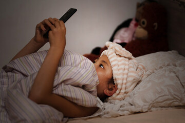 ベッドでスマートフォンを使う少女