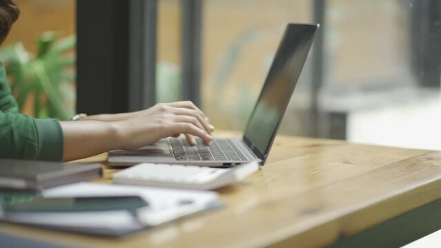 Beautiful and smart Asian woman with a happy mood and smile using a laptop computer in a coffee shop Confident and attractive freelance woman working typing on laptop at coffee shop 4K