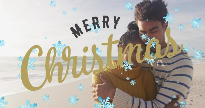 Animation of merry christmas text and snow falling over biracial couple at beach