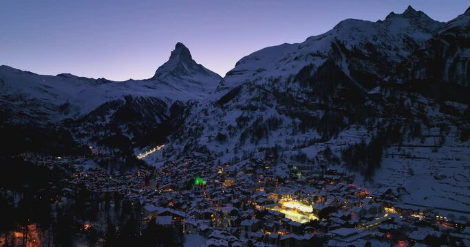Aerial drone shot of Zermatt city Valley famous travel ski resort and iconic Matterhorn peak at dawn in the swiss alps, Switzerland. The snow covered village and church in Canton Valais in winter.