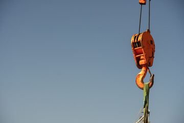 Hook bottle of a crane with ropes, eyelets, link chain and hook against a blue sky. The equipment...