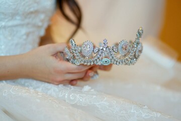 Women's hands of the bride in a wedding dress with a crown for the head. Jewelry for the bride.