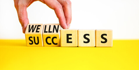 Wellness for success symbol. Concept words Wellness and Success on wooden cubes. Businessman hand. Beautiful yellow table white background. Business wellness for success concept. Copy space.