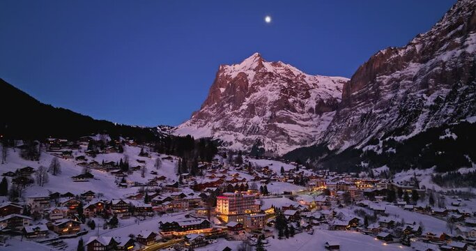 Panorama aerial Drone shot of Cottages chalets in Murren village at snowy winter night. M&uuml;rren traditional Walser mountain village in the Bernese Highlands of Switzerland. popular tourist spots.