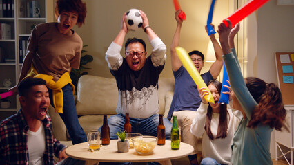 Fototapeta na wymiar Happy Asian people with friends watching soccer or football on tv and celebrating victory at home, world cup football cheering concept
