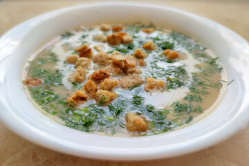 mushroom soup puree with croutons and dill in a white plate