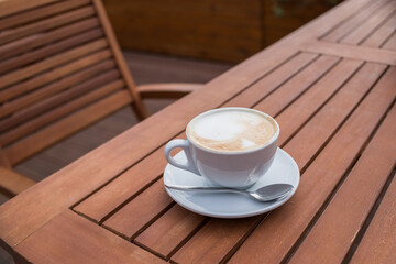 Caffe Latte. Cup of coffee with a sweet cookie. Good morning drink. Rustic wooden background. Close up.Breakfast coffee, Cappuccino art on vintage wooden table