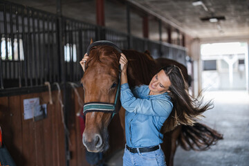 Woman taking care of her horse in stable
