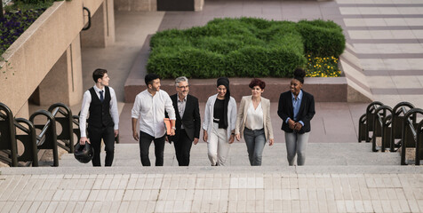 Colleagues talking as they walk down the steps, multiracial diverse business group, leaving work. - Powered by Adobe
